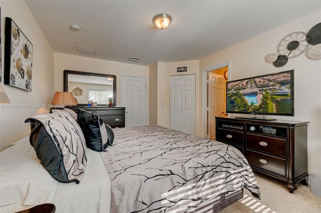 bedroom with a textured ceiling and light colored carpet