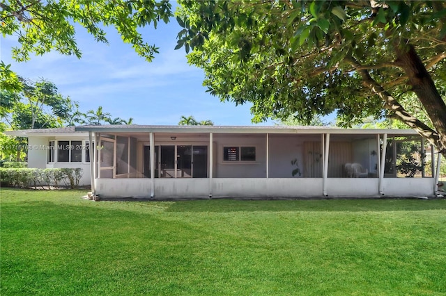 rear view of property featuring a lawn and a sunroom