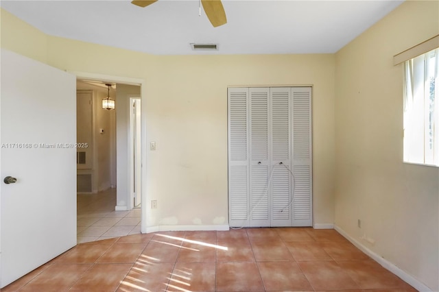 unfurnished bedroom featuring ceiling fan, light tile patterned floors, and a closet