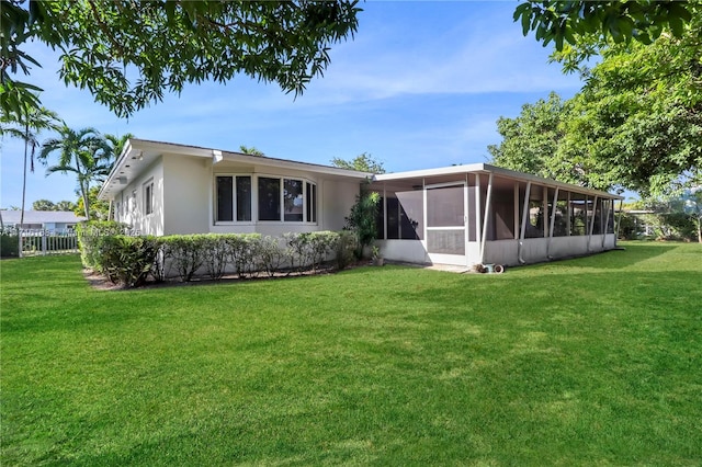 back of property featuring a sunroom and a yard