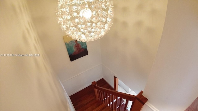 stairs featuring hardwood / wood-style floors and a notable chandelier