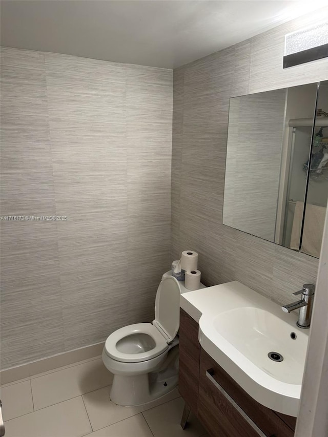 bathroom with walk in shower, tile patterned floors, toilet, vanity, and tile walls