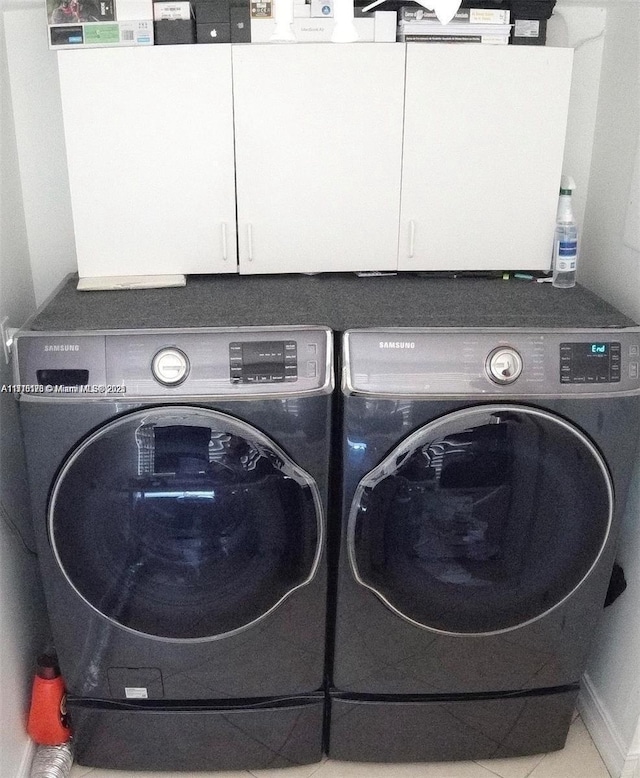 washroom with tile patterned flooring, cabinets, and independent washer and dryer