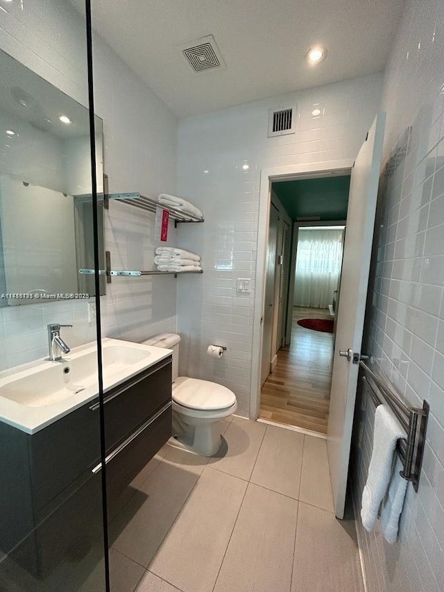 full bath featuring toilet, visible vents, tile walls, and tile patterned floors