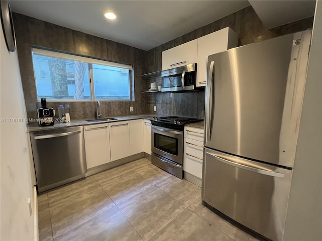 kitchen with tasteful backsplash, white cabinets, appliances with stainless steel finishes, open shelves, and a sink