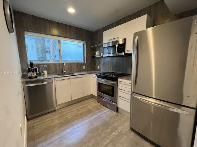 kitchen featuring a sink, white cabinets, appliances with stainless steel finishes, backsplash, and open shelves