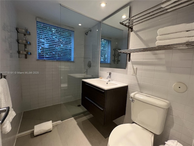 bathroom featuring tiled shower, toilet, vanity, tile walls, and recessed lighting