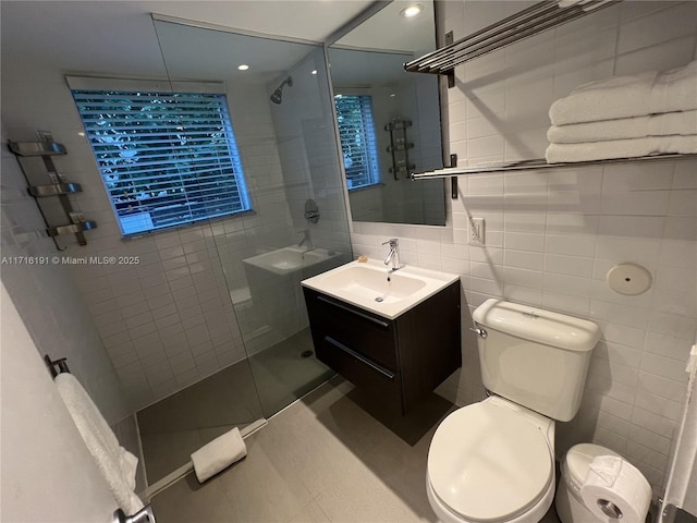 bathroom featuring toilet, vanity, tile walls, and tiled shower