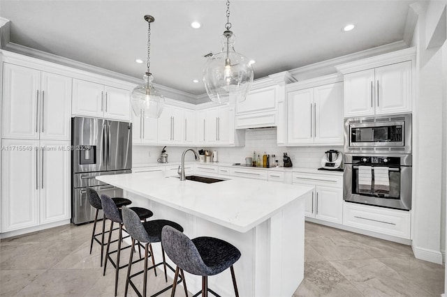 kitchen featuring pendant lighting, a kitchen island with sink, sink, appliances with stainless steel finishes, and white cabinetry