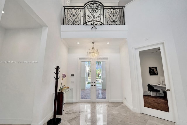 foyer with a towering ceiling, crown molding, and french doors