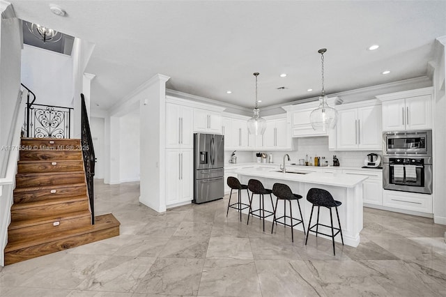 kitchen with pendant lighting, white cabinets, a center island with sink, and stainless steel appliances