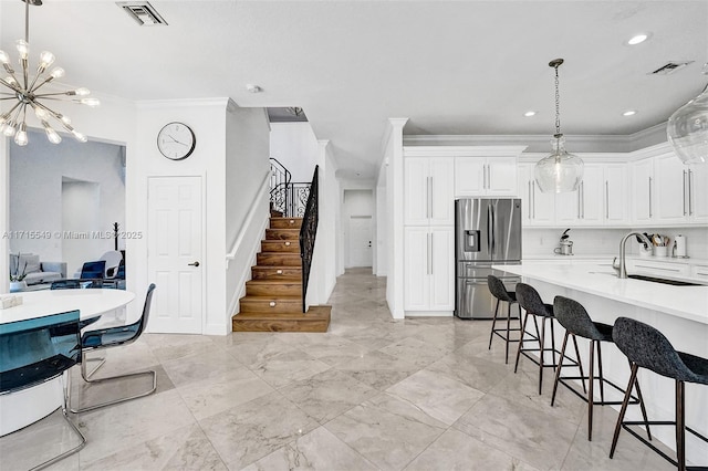 kitchen with sink, a kitchen breakfast bar, stainless steel fridge, crown molding, and white cabinets