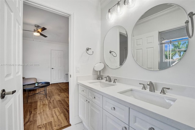 bathroom featuring ceiling fan, hardwood / wood-style floors, vanity, and ornamental molding