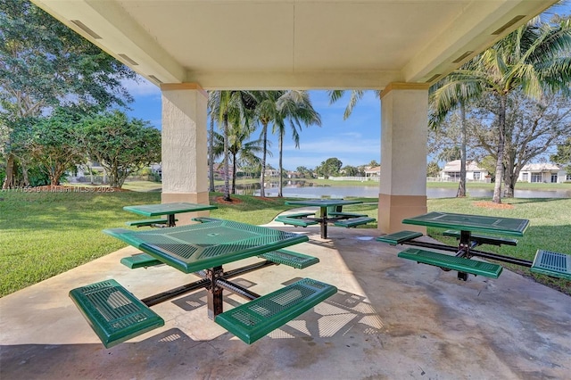 view of property's community with a lawn, a water view, and a patio