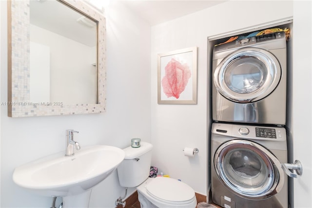 bathroom with sink, stacked washer and clothes dryer, and toilet