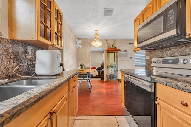 kitchen featuring appliances with stainless steel finishes, backsplash, a wall mounted AC, light tile patterned floors, and hanging light fixtures