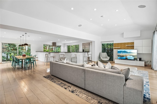 living room with light wood-type flooring, vaulted ceiling, and a healthy amount of sunlight