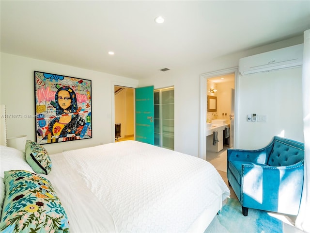 bedroom featuring ensuite bath and an AC wall unit