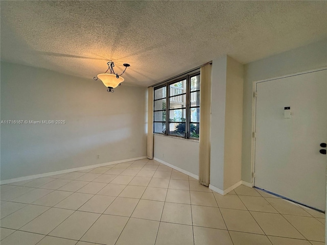 empty room featuring light tile patterned floors and a textured ceiling