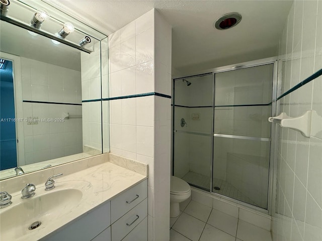 bathroom featuring tile patterned floors, vanity, a shower with shower door, and toilet