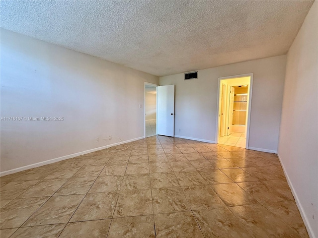 spare room featuring light tile patterned floors and a textured ceiling