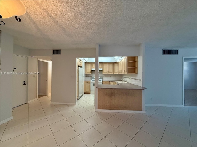 kitchen with kitchen peninsula, light brown cabinetry, white appliances, sink, and light tile patterned flooring