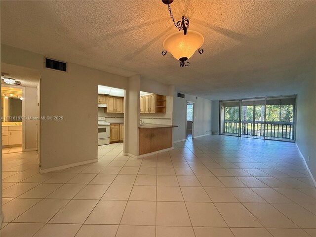 unfurnished living room with floor to ceiling windows, sink, light tile patterned floors, and a textured ceiling