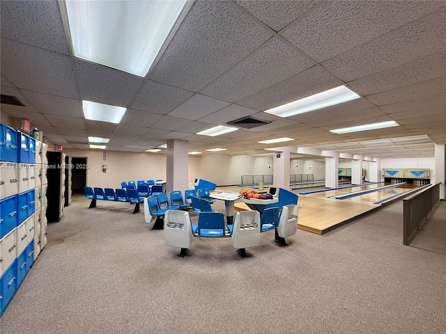 interior space with a drop ceiling, a bowling alley, and carpet floors