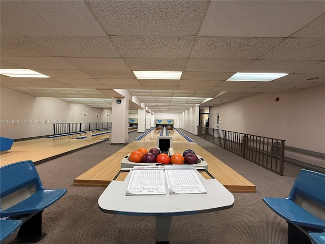 interior space featuring a drop ceiling, carpet floors, and a bowling alley