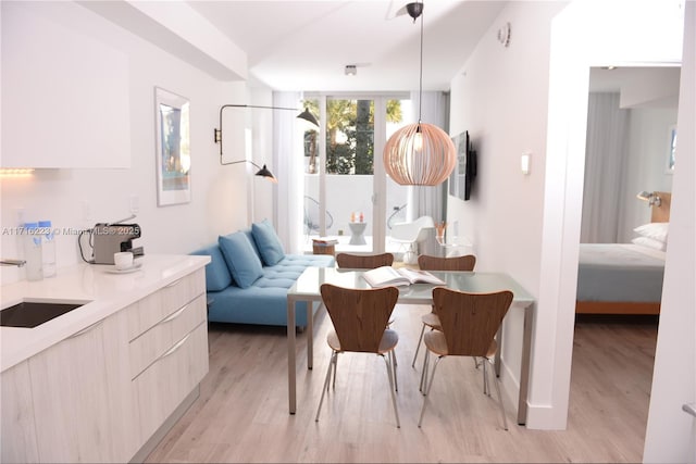 dining space featuring a wall of windows, light wood-type flooring, and sink