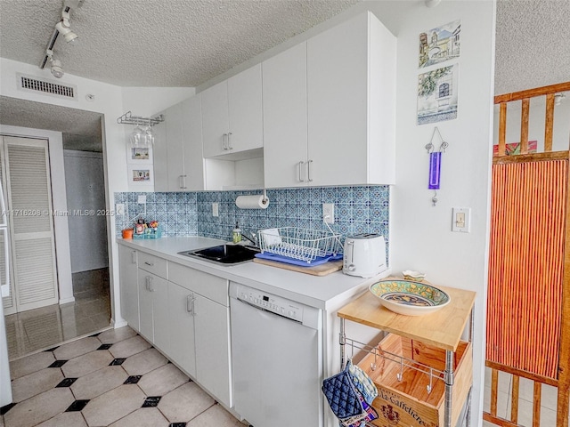 kitchen featuring white dishwasher, sink, white cabinetry, and backsplash