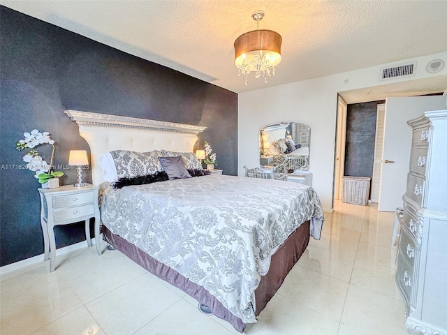 bedroom featuring a notable chandelier, light tile patterned floors, and a textured ceiling