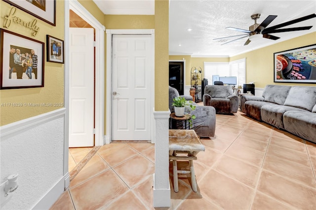 tiled living room featuring a textured ceiling, ceiling fan, and crown molding