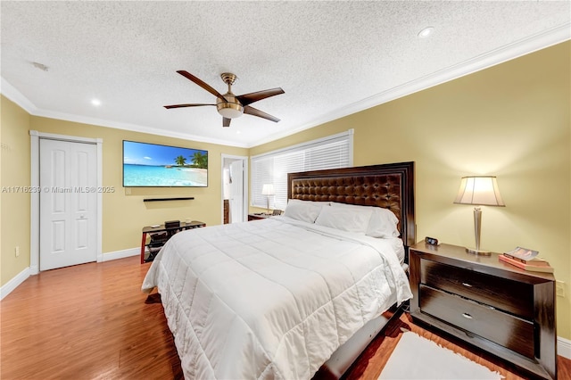 bedroom with a textured ceiling, hardwood / wood-style flooring, ceiling fan, and crown molding