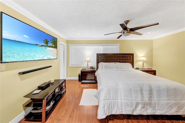 bedroom with ceiling fan, light wood-type flooring, a textured ceiling, and ornamental molding