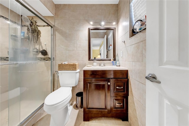 bathroom with a shower with door, vanity, tile walls, and toilet