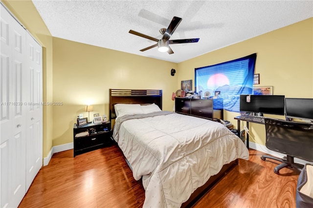 bedroom with hardwood / wood-style flooring, ceiling fan, a textured ceiling, and a closet