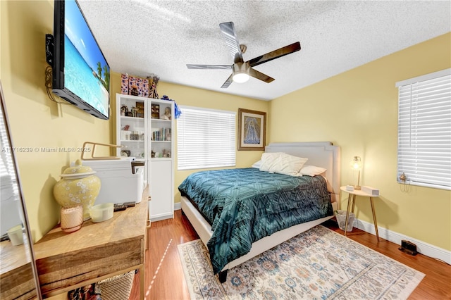 bedroom with hardwood / wood-style flooring, ceiling fan, and a textured ceiling