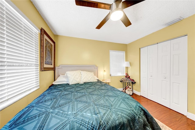 bedroom featuring ceiling fan, a closet, hardwood / wood-style floors, and a textured ceiling