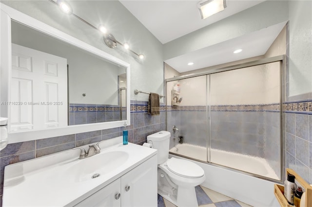 full bathroom with vanity, toilet, bath / shower combo with glass door, and tile walls