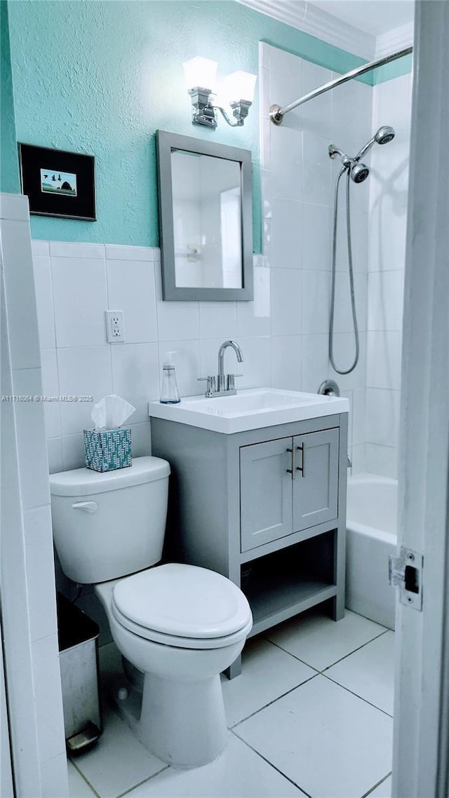 full bathroom with vanity, tiled shower / bath combo, tile walls, tile patterned flooring, and toilet