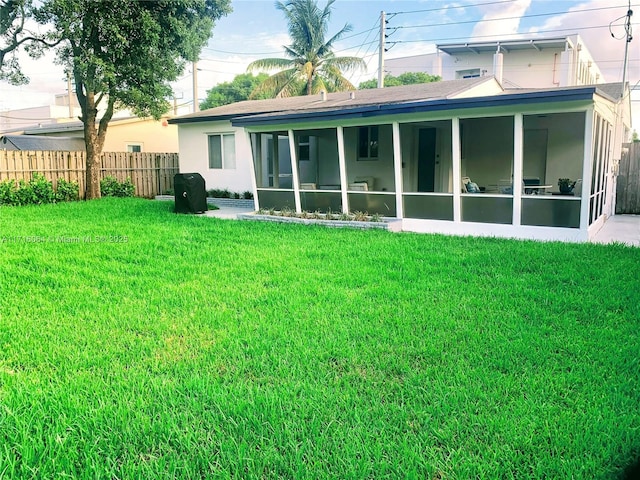 back of property with a sunroom and a yard