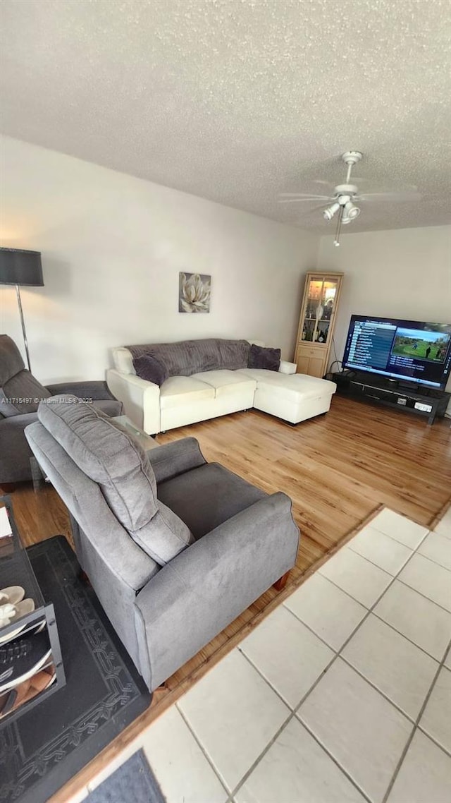 tiled living room with ceiling fan and a textured ceiling