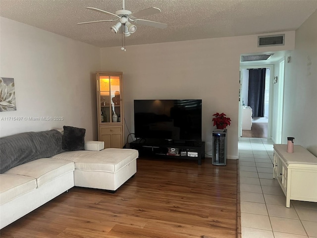 living room featuring tile patterned floors, ceiling fan, and a textured ceiling