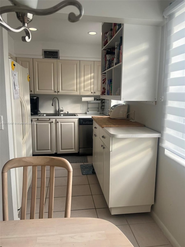 kitchen with dishwasher, light tile patterned floors, white fridge, and sink