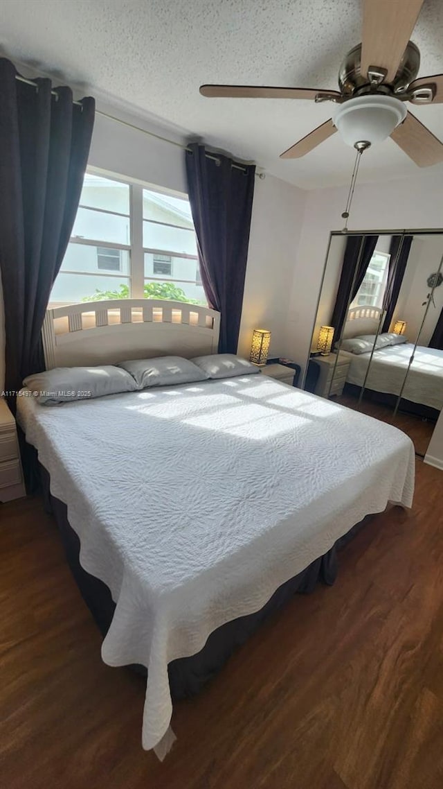 bedroom with ceiling fan, dark hardwood / wood-style flooring, and a textured ceiling