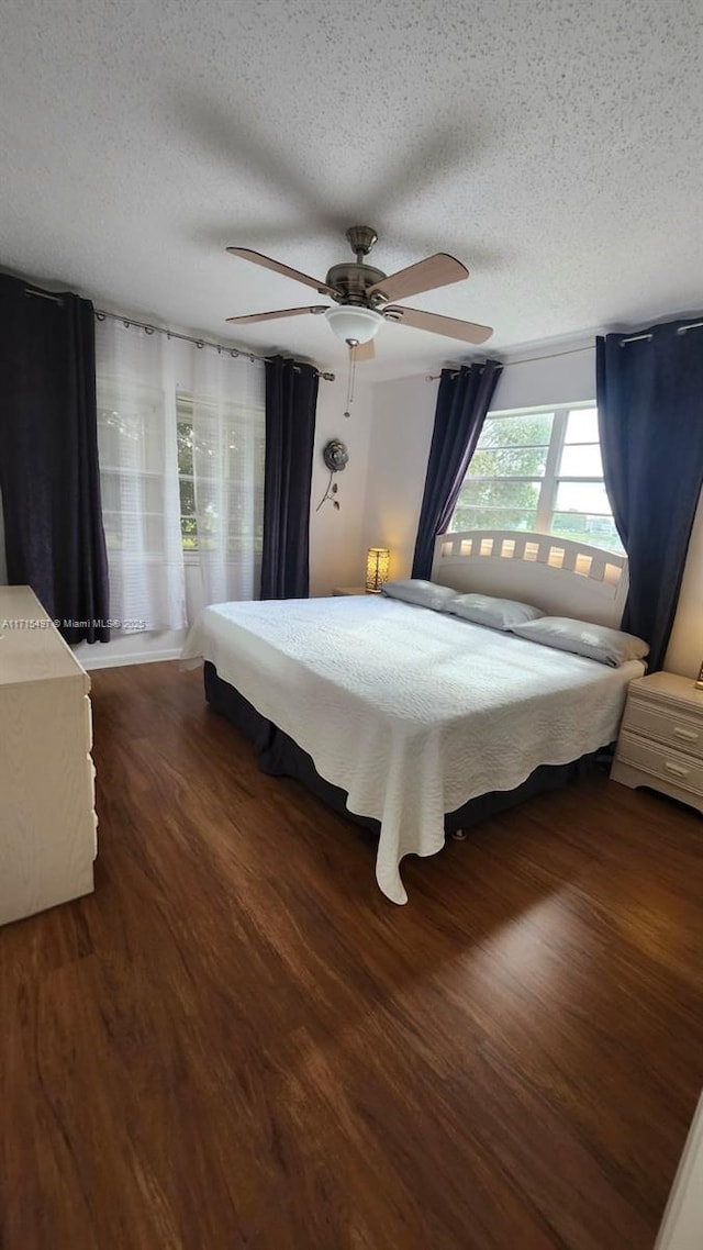 bedroom featuring a textured ceiling, ceiling fan, and dark wood-type flooring