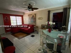 tiled living room with ornamental molding and ceiling fan