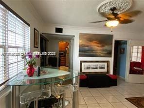 tiled dining room with ceiling fan and ornamental molding