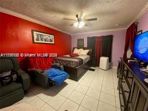 tiled bedroom with crown molding, ceiling fan, and a textured ceiling